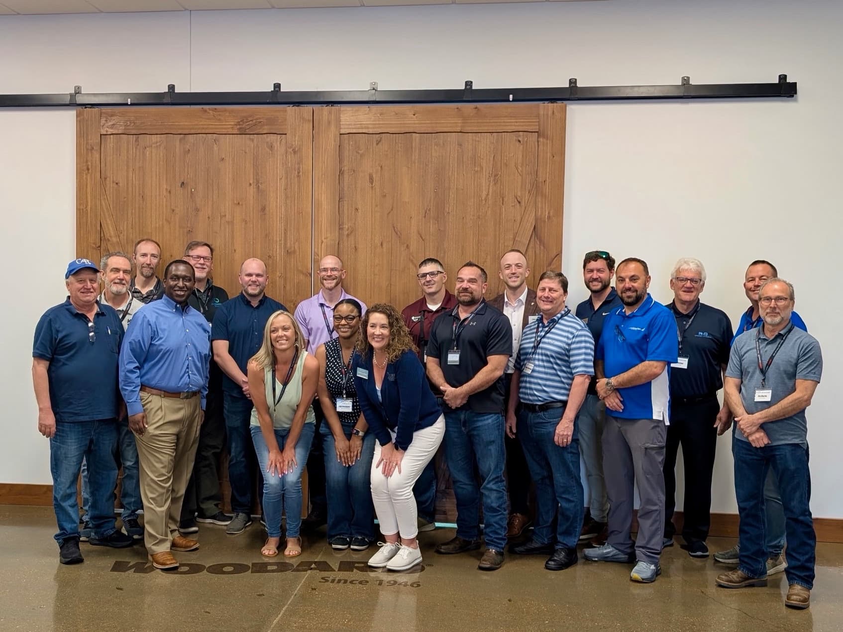 About twenty chapter members standing together in front of a pair of wooden barn doors at a member event